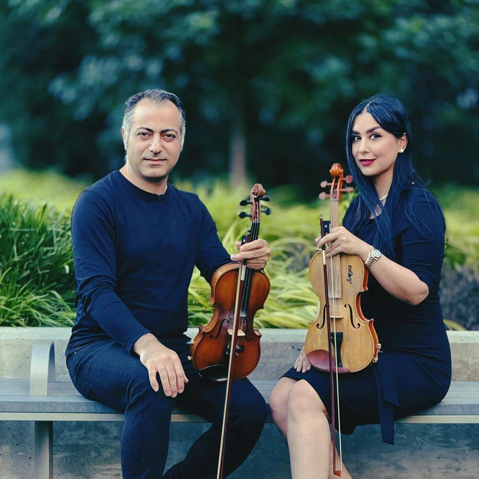 Ali and Yas seated outdoors with their violins